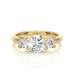 Load image into Gallery viewer, Front view of 2 Carat Round Moissanite Three Stone Engagement Ring In Yellow Gold, highlighting the brilliant center moissanite stone.